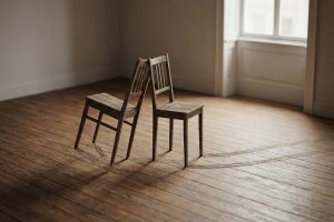 Deux chaises se faisant face, l'une est tirée en arrière, laissant des traces au sol.