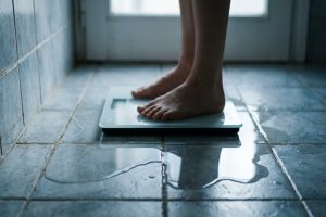 Pieds nus sur une balance posée dans une flaque d'eau, illustrant la perte de poids illusoire.