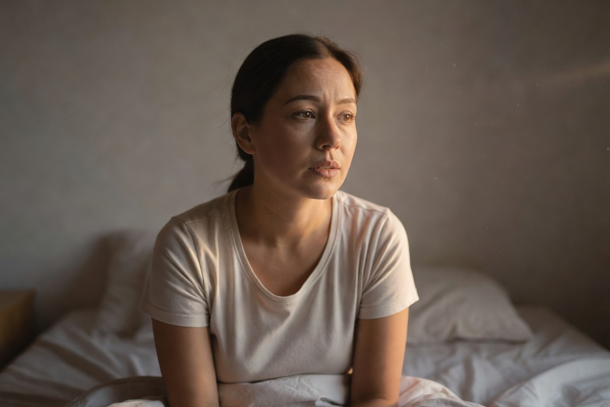 Femme assise dans son lit au lever du soleil, réfléchissant à un rêve