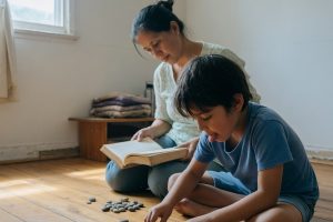 Enfant alignant des pierres au sol avec sa mère observant