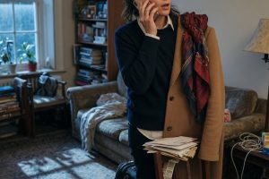 Femme au téléphone dans un salon lumineux avec manteau accroché