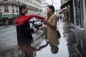 Silhouettes d'un homme et d'une femme reflétées dans une flaque sur le trottoir