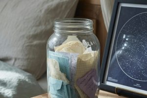 Bocal de notes pliées et carte céleste sur table de chevet au matin