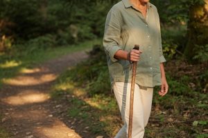 Femme marchant avec une canne en forêt au coucher du soleil